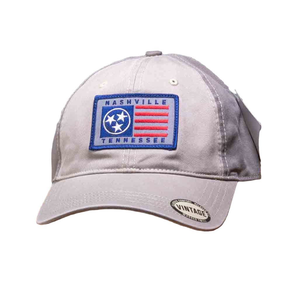 This Tri Star Nashville Tennessee Trucker Hat features a rectangular patch with an embroidered TN state flag along with the iconic Three Stars and Nashville Tennessee in Navy stitching.  The Nashville trucker hat has a stiff, rounded khaki colored bill in a relaxed fit vintage washed twill and a cloth front crown. The body has two matching front khaki panels and the remainder are in a darker olive/khaki color.