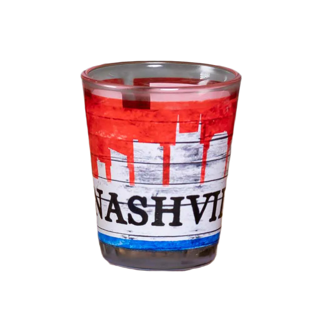 A new design Nashville Skyline Shot glass printed in red, white and blue with a bold "NASHVILLE" in black.