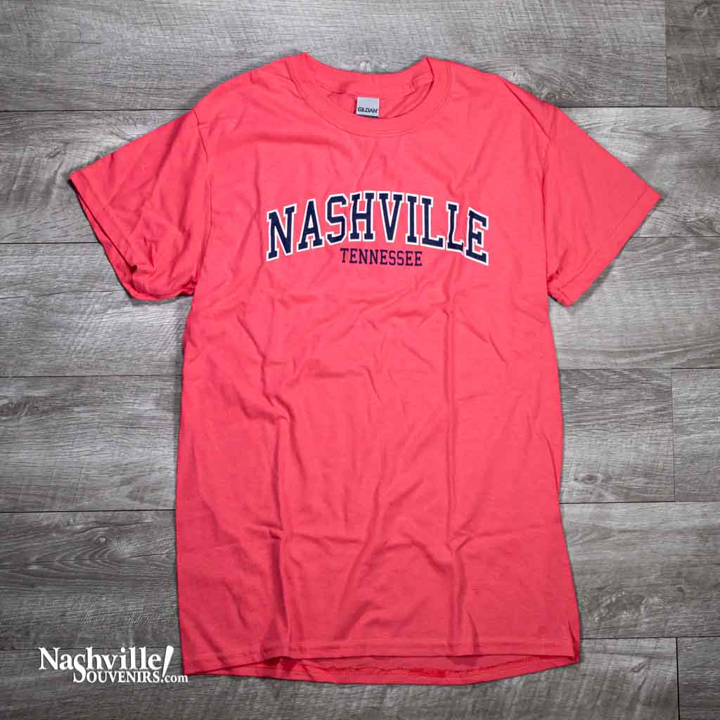 Classic Nashville themed t-shirt featuring a large Nashville logo in white and blue on a coral red body. Made of 100% cotton.