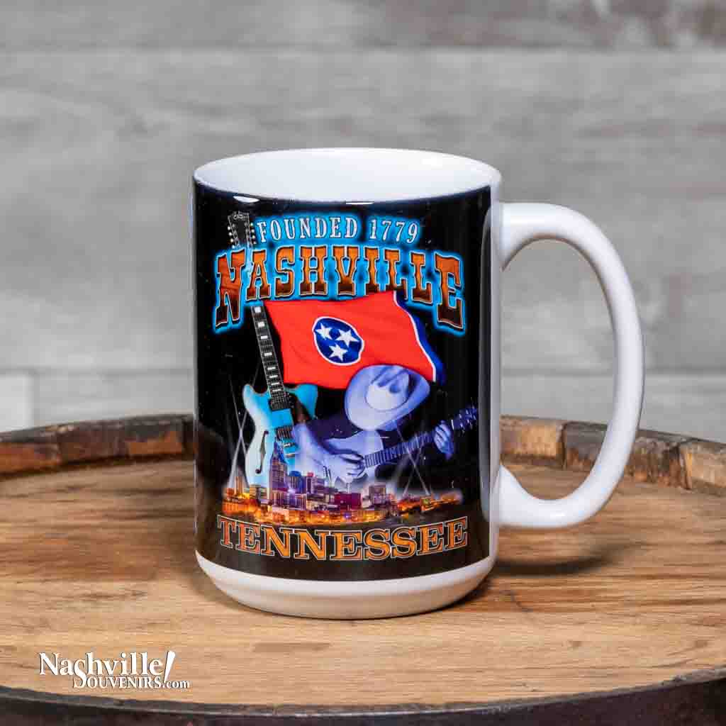 This "Founded 1779" Nashville Coffee Mug is a white ceramic mug with an easy to grip handle. The mug features a two sided colorful design that includes images of the TN state flag, downtown Nashville and a picker playing an acoustic guitar.