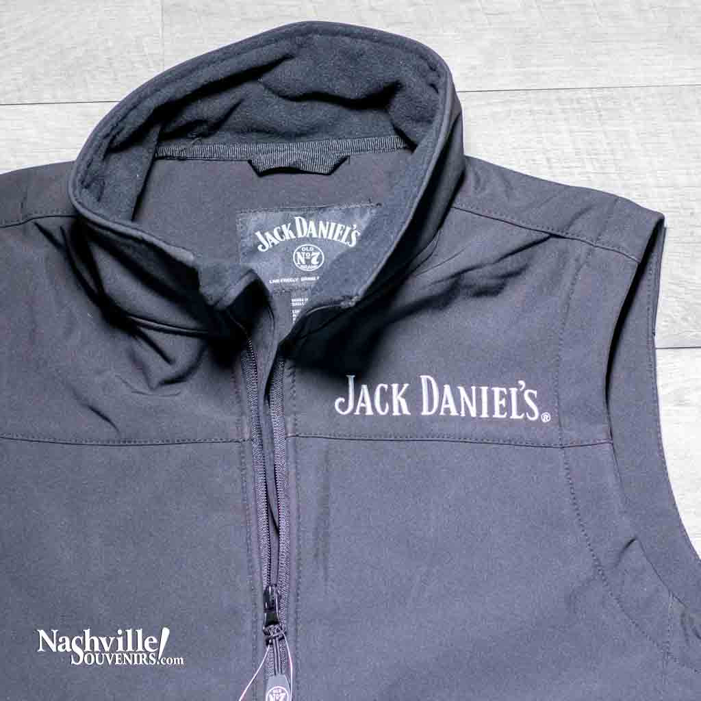 Closeup of an Officially licensed Jack Daniels vest made of soft shell polyester with a zip-up front. Has Jack Daniels embroidered on the front left chest and also has the circular Old No.7 Brand round logo on the back below the neck area.