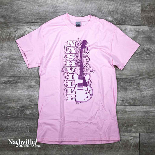 A pink Nashville Guitar t-shirts feature a large Nashville alongside an electric guitar. There is a nice filigree pattern in the background as well.