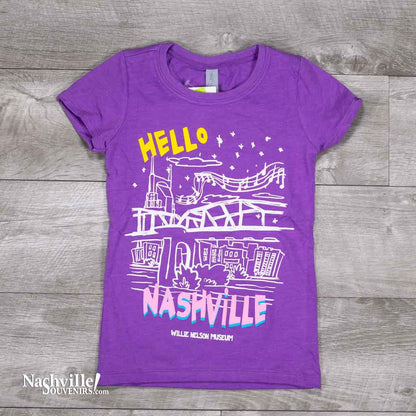 kids purple color Hello Nashville Youth T-Shirt features a colorful glow-in-the-dark logo with the Nashville skyline and Willie Nelson Museum at the bottom of the t-shirt.