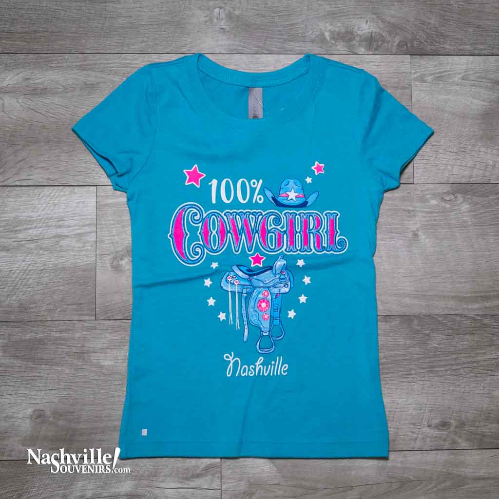 Our new design, youth "100% Cowgirl Nashville" T-Shirt features a colorful, glittery logo that includes a cowgirl hat along with the side view of a saddle with Nashville printed below.  This shirt is available in either Pink or Bondi Blue and comes in youth sizes X-Small, Small, Medium and Large.